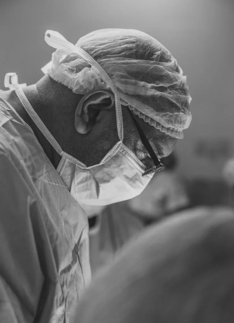 Un chirurgien en blouse blanche dans un hôpital, capturé en noir et blanc.