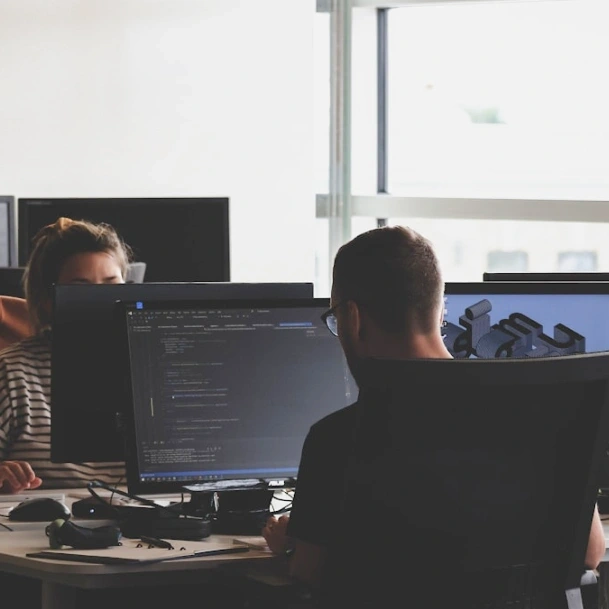 Deux personnes travaillant sur des ordinateurs dans un bureau moderne.